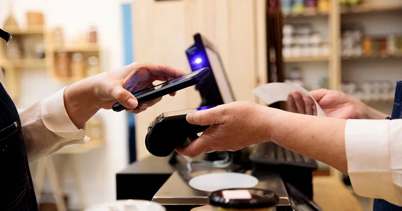 A close-up of a person using a smartphone for a contactless payment at a store.