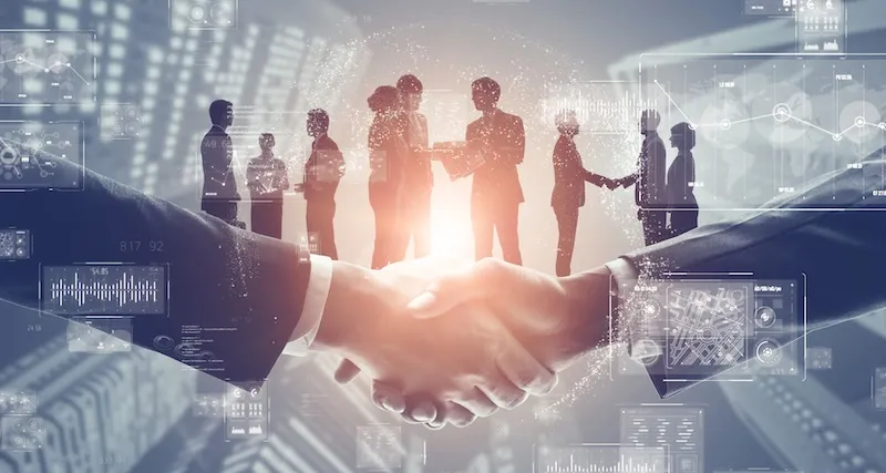 Two people shaking hands with people in the background